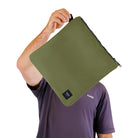 Person holding a green zippered pouch with a visible brand logo on a white background