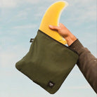 Person holding a green bag with a yellow crescent moon design against a blue sky.